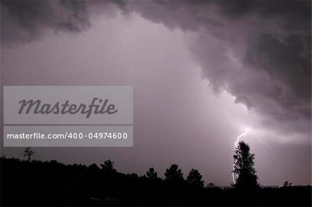 Lightning bolt behind tree from an Ominous storm