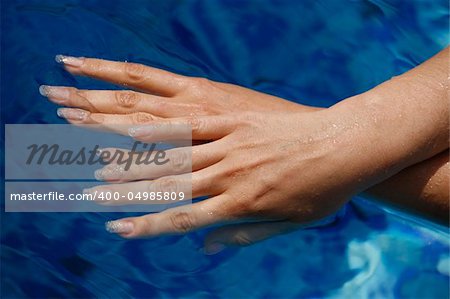 Beautiful female hands in blue water