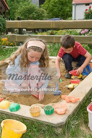 boy and girl playing in sand box