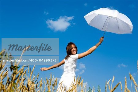 Happy young girl with umbrella in the field. Smiling face