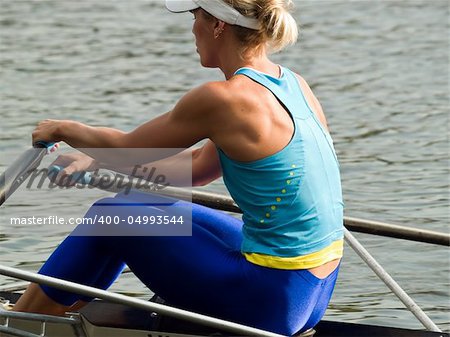 Sporty young lady rowing in boat on water rear view