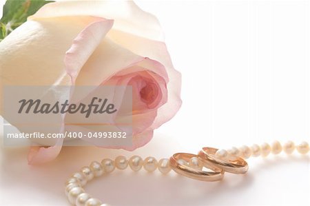 Wedding rings, pearl beads and rose over white, isolated, with clipping path