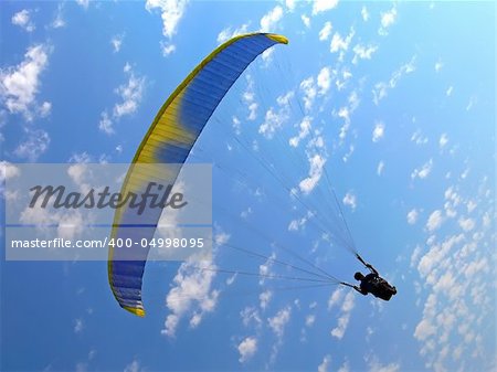 paraglide (parachute) flying under blue cloudy sky