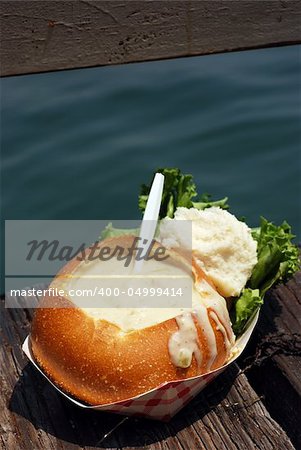 Clam chowder in a sourdough bread bowl on a wooden fishing dock