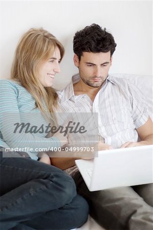 A young woman suggestively approaches her man who is working on his laptop