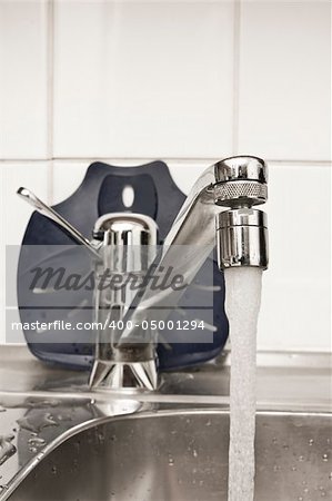 Chrome tap in the kitchen with flowing water