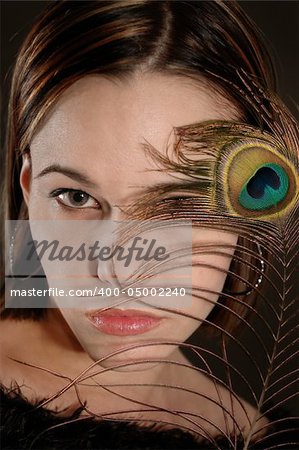 Portrait of female beauty holding peacok feather by her face