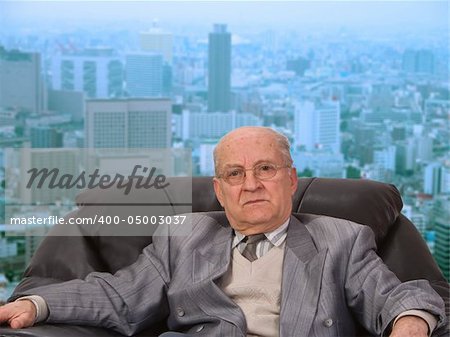 Portrait of an old businessman in front of the office window in a big city.Shot with Canon 70-200mm f/2.8L IS USM