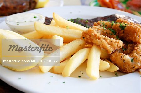 Deep fried calamari and chips together with juicy pork ribs on a plate.