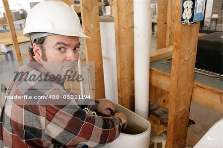 A construction plumber fixing a toilet on new building construction.