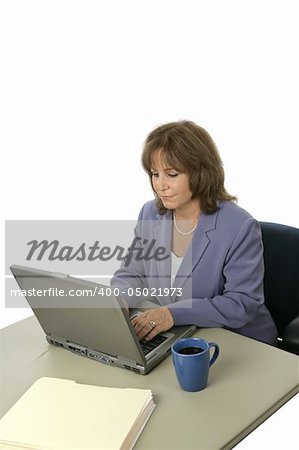 A mature female executive working on her laptop.  Isolated on white. Vertical view.