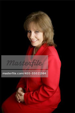 A pretty, friendly woman in a red business suit.  Black background.
