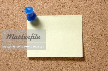 Yellow post-it note with blue pushpin on corkboard
