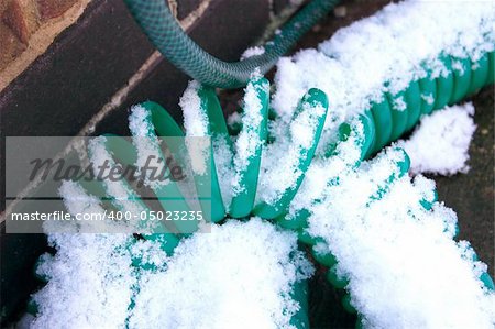 coiled hosepipe left out in the snow