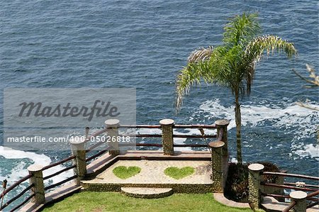 A romantic setting for two people that is formed by two hearts of grass built into a rock promontory over the ocean.