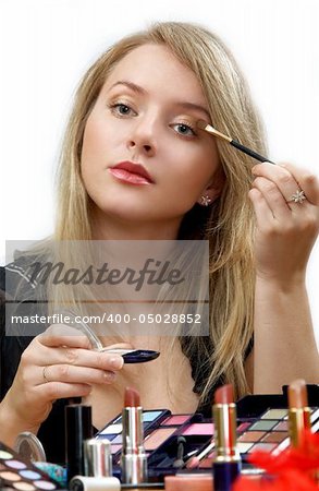 young beautiful woman is making up for itself in front of a mirror