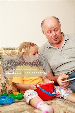Grandpa and grand-daughter reading and playing