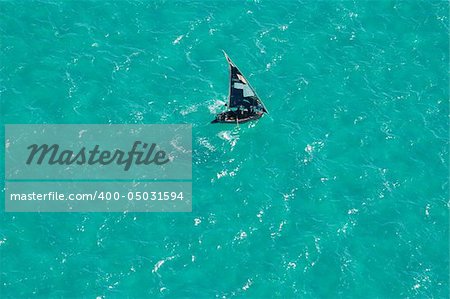 Aerial view of a small sailboat (called a dhow) on the open sea, Mozambique