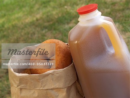 a half-gallon of apple cider beside a bag of donuts