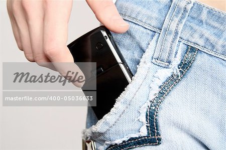 The hand gets a mobile phone from a pocket of jeans