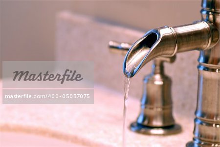 Side view up of a faucet with running water