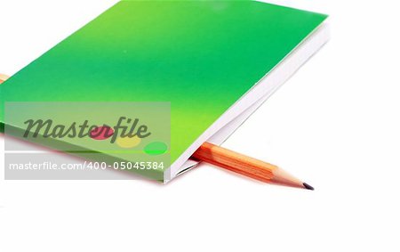 The pencil is inserted into a green notebook