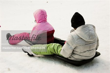 kids tobogganing on a warm winter day