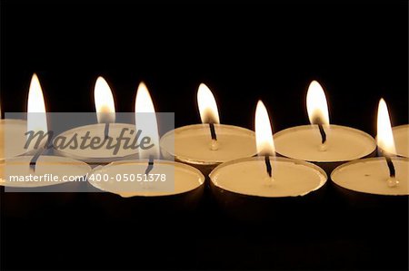 close up on two rows of candles on dark background