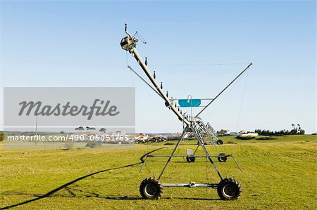 Resting irrigation pivot in a green grass field near a small village. Alentejo, Portugal