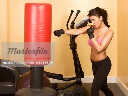 Attractive woman kickboxing with red punching bag