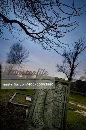 A spooky graveyard with a deep blue sky and an angel tombstone