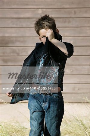 Little boy hides his face behind the tail of his own shirt.