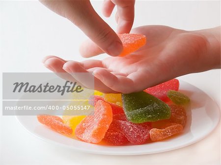 Woman's hands taking the sweet marmalade pieces from the plate