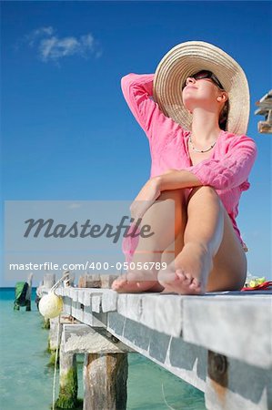 One of a large series. Woman in pink kaftan sunbathing on a tropical boardwalk