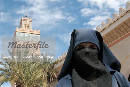 A veiled, Muslim lady in front of a Mosque.