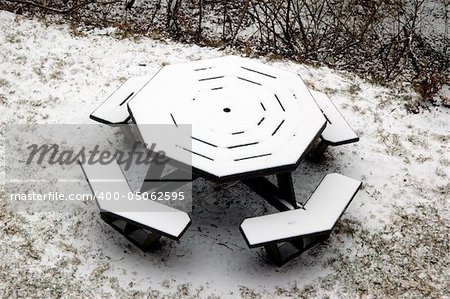 A picnic table fully covered in snow