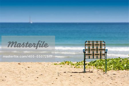 Chair sits on an inviting tropical shore.