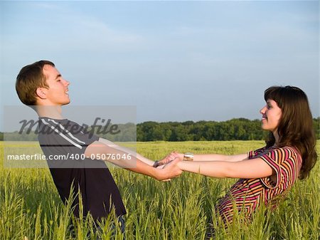 Teen Couple Holding hands Field looking each other