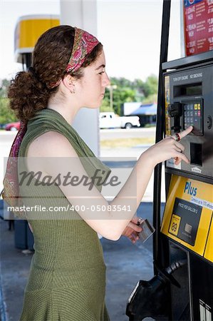 Young woman uses her ATM card to pay for gasoline.