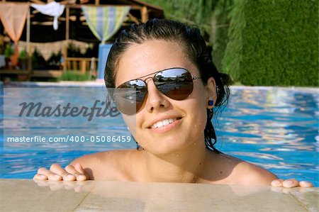 beautiful young woman posing in swimming pool in summer