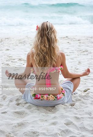 Blond girl sitting in lotos position on the beach