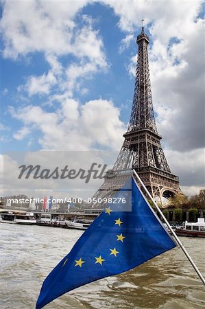 View at Eiffel tower across the Seine River from boat. European Union flag in front.