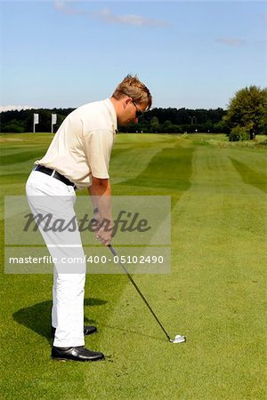 A golf player strikes a shot