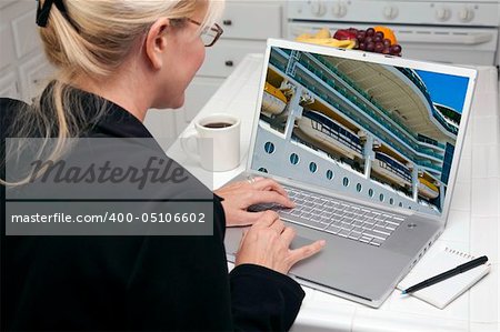 Woman In Kitchen Using Laptop to Research Travel, Vacation and Cruises. Screen can be easily used for your own message or picture. Picture on screen is my copyright as well.