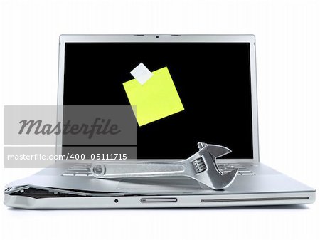 Damaged laptop with a spanner over it and a blank post-it on the screen. Isolated on white.