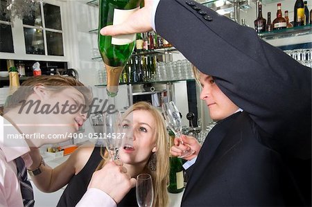 three young, drunken adults taking the last drop of champagne at a bar