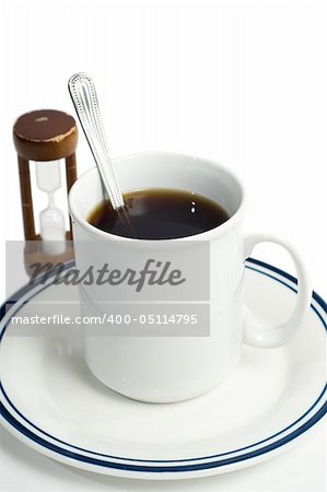 A stirred cup of coffee and an hourglass, shot against a white background