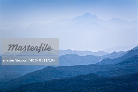 Mountain peaks covered with dark woods in blue mist. Montenegro.