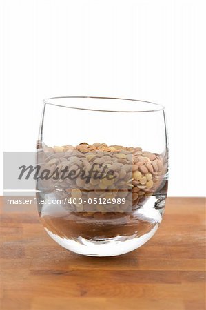 lentils in glass on wooden table, white background