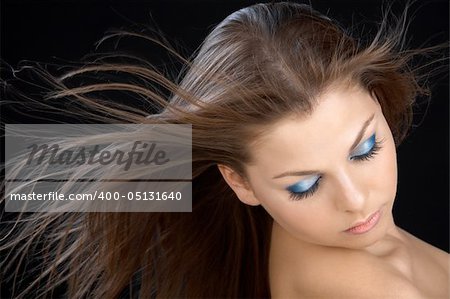 The beautiful girl with a flying hair on a black background